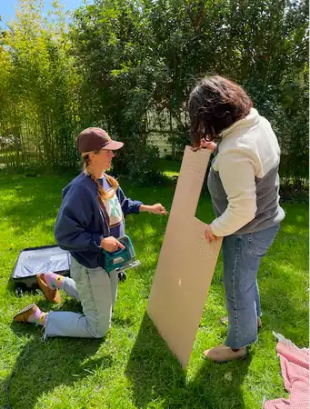 Image 4. Sophie and Hannah cutting right dimensions of peg board with a hand held saw.